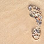 Footprint in the sand, filled with shells, symbolising how fulfilling life can be when we are present in the moment