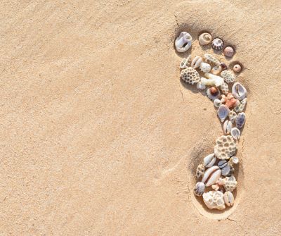 Footprint in the sand, filled with shells, symbolising how fulfilling life can be when we are present in the moment
